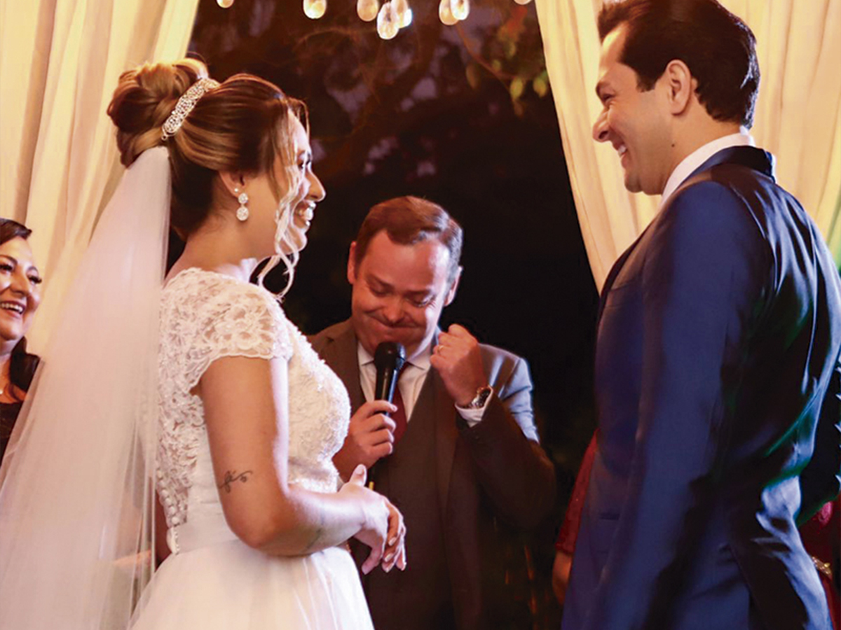 Camilo Lelles celebrando casamento com microfone entre os noivos