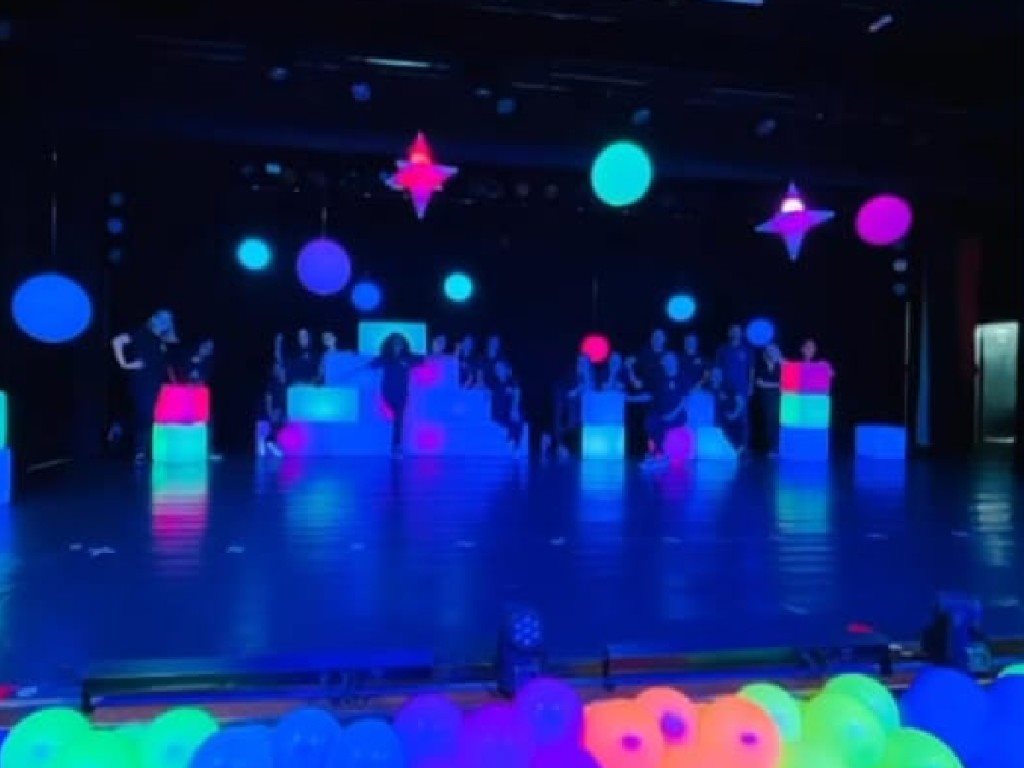 Equipe e formandos no palco de festa de formatura com decoração neon