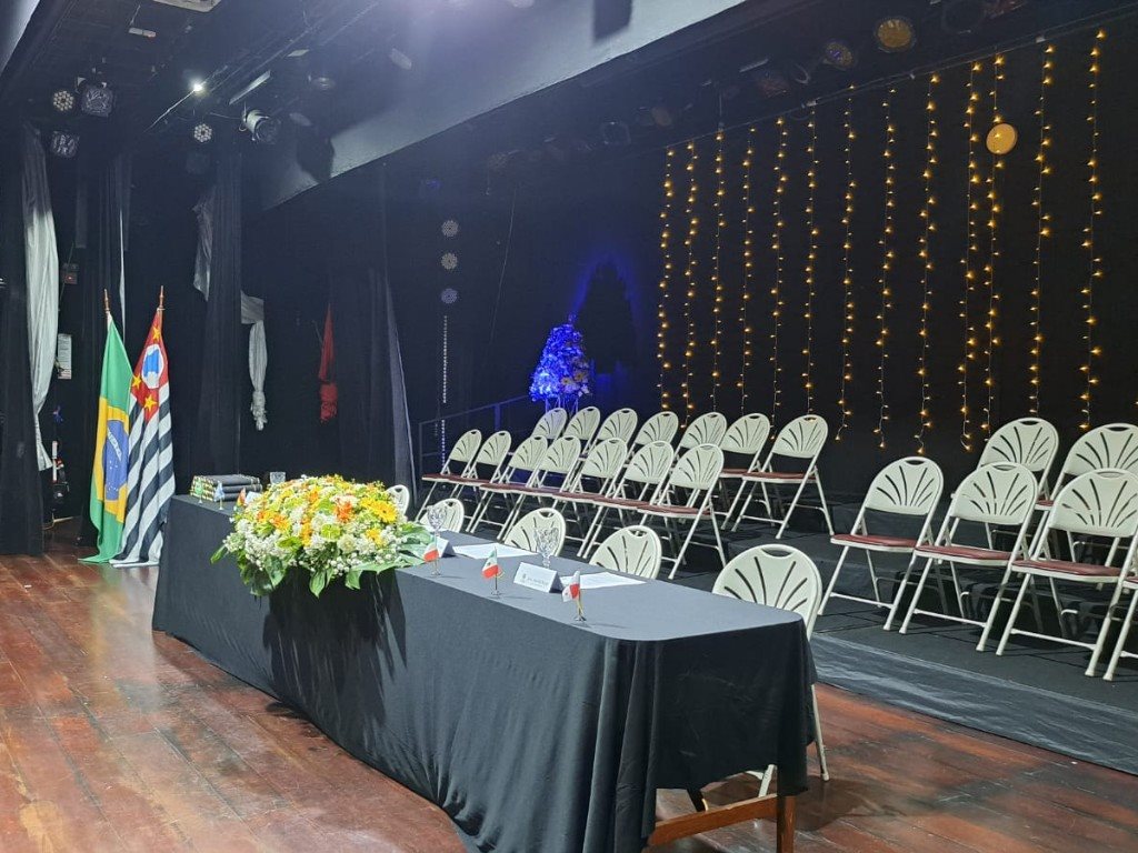 Palco montado para colação de grau com mesa, cadeiras e iluminação
